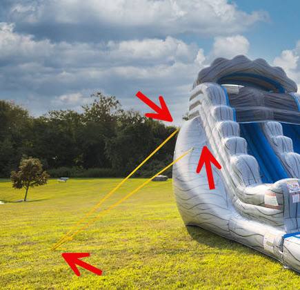 Inflatable waterslide staked down with yellow anchor straps in a grassy yard
